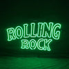 Green neon sign reading “ROLLING ROCK” with large text on dark background