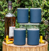 Set of four blue insulated whiskey lowball tumblers on a wood outdoor stump