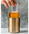 Glass lined whiskey lowball with hand inserting whiskey into clear glass insert