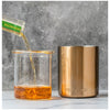 Glass lined whiskey lowball with poured whiskey and clear glass insert; bronze base