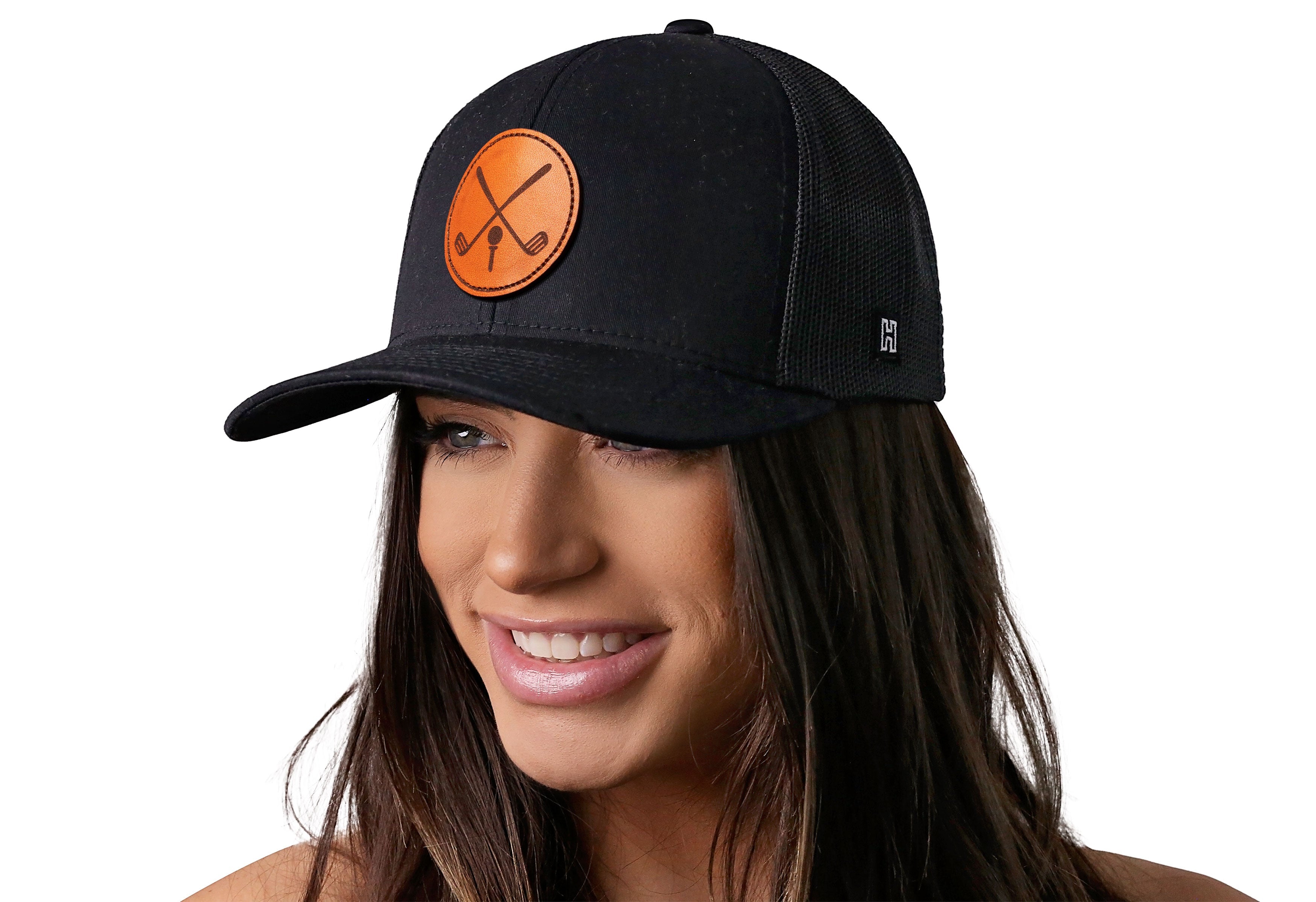 Black trucker cap with orange crossed-clubs leather patch, worn by woman