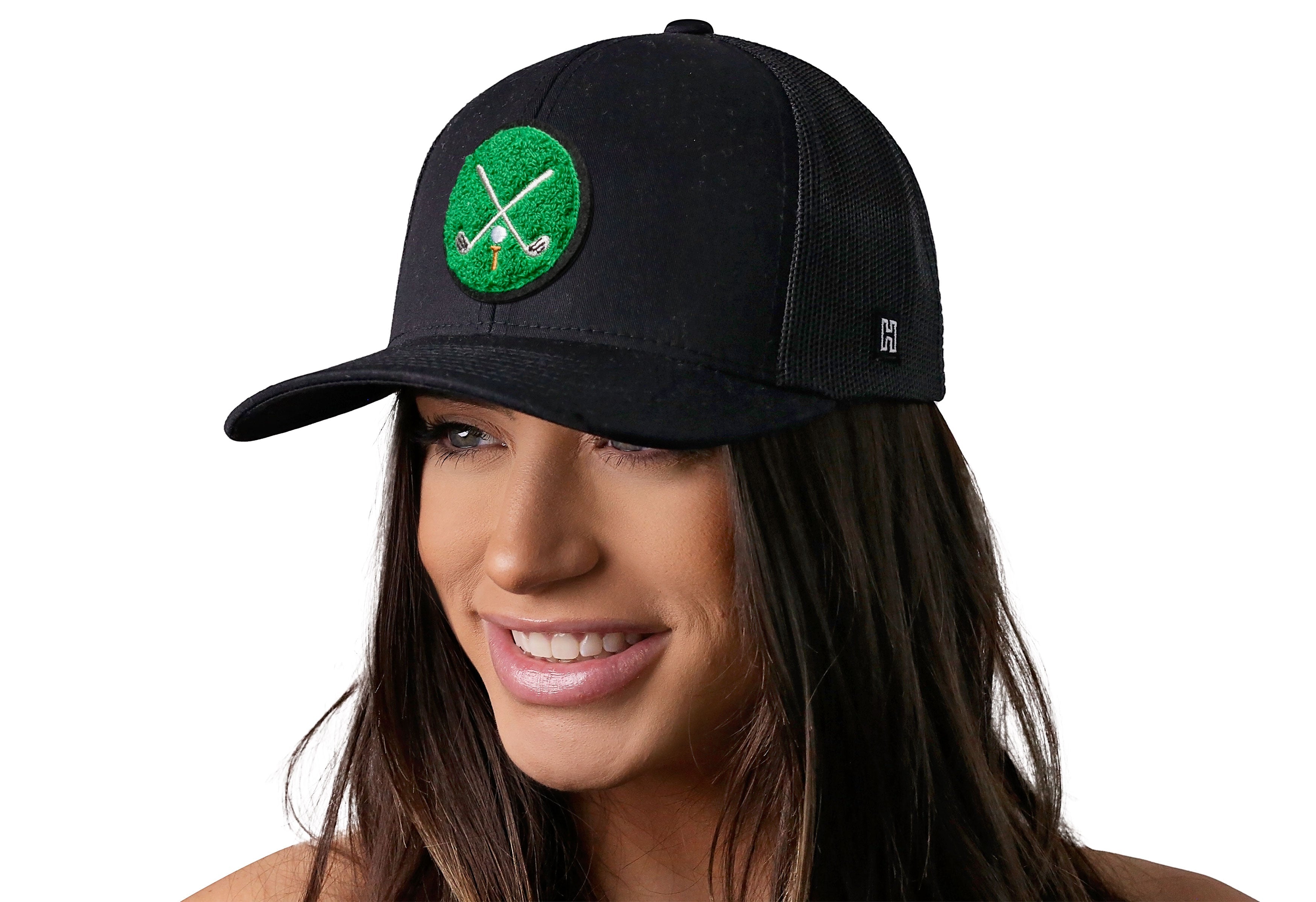 Black trucker cap with green crossed clubs patch worn by woman, front mesh panels.