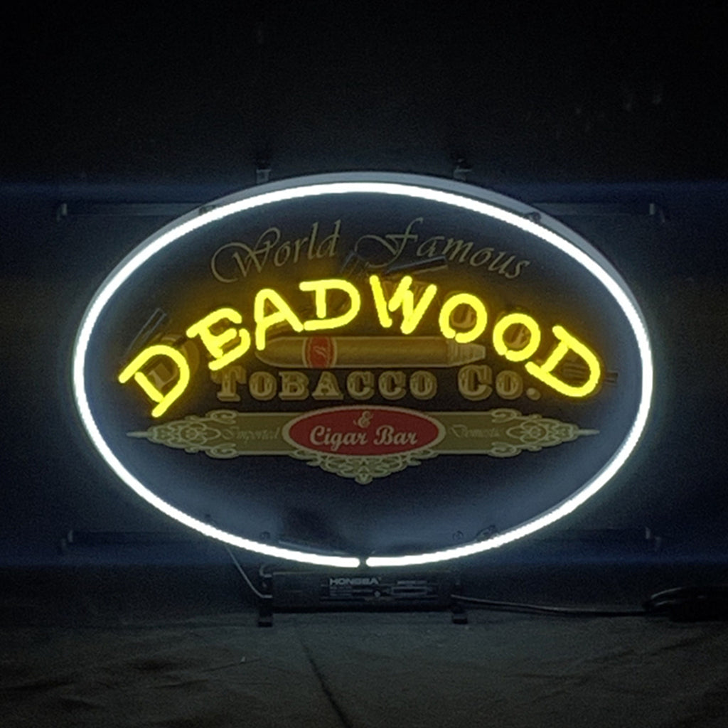 Oval neon sign with bright yellow 'DEADWOOD' and 'Cigar Bar' center text
