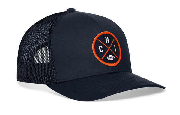 Navy trucker hat in side profile with orange logo patch and mesh back, snapback