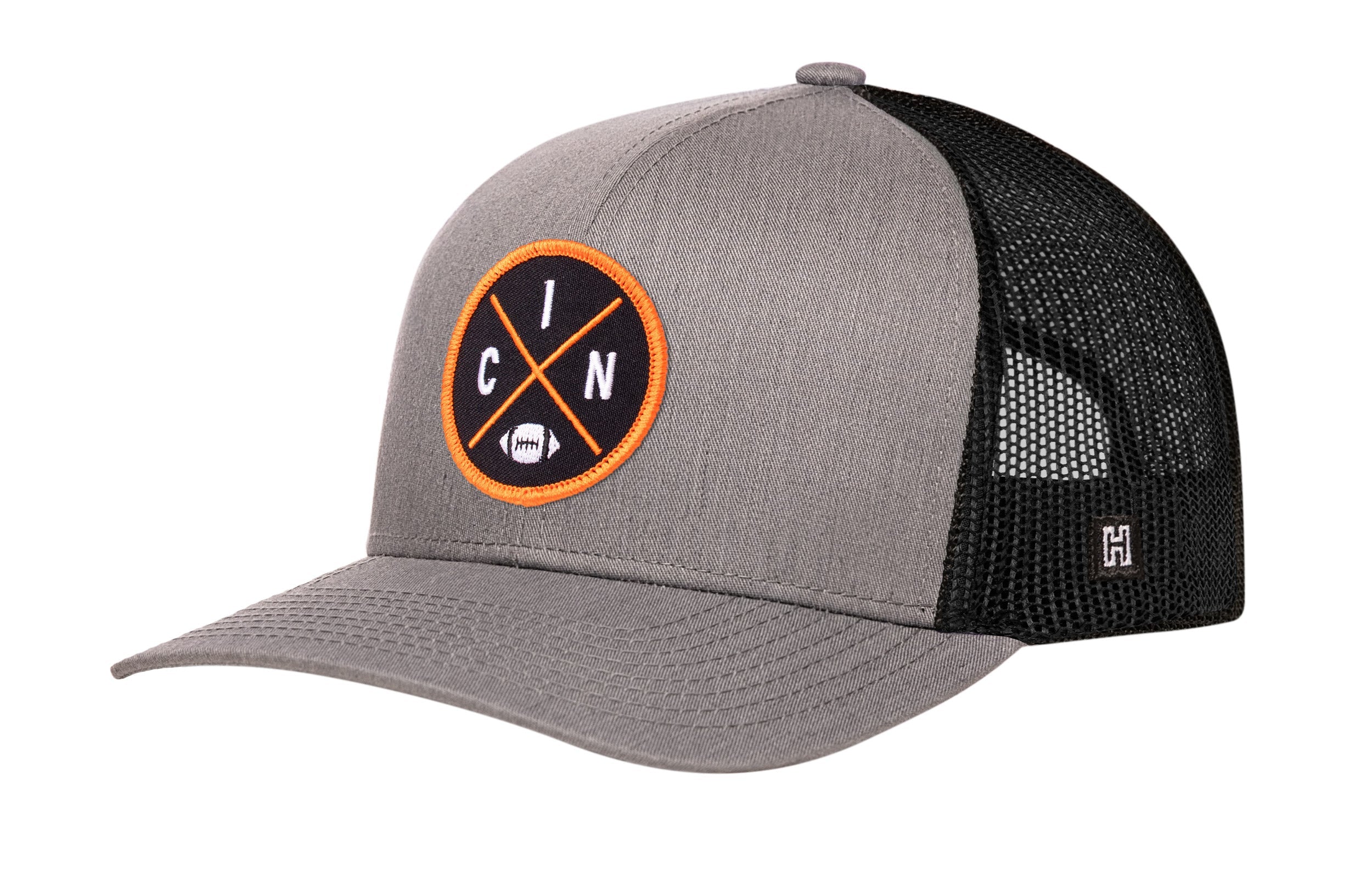 Gray trucker snapback cap with black mesh back and orange circular logo patch.