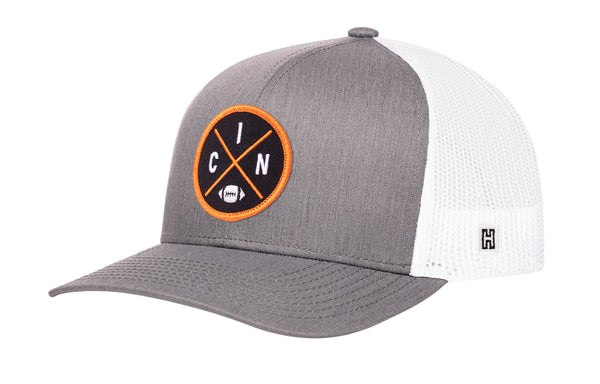 Gray trucker snapback cap with white mesh back and orange circular logo patch.
