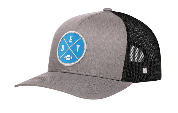 Gray and black trucker hat with blue DET X logo patch, curved brim, and mesh back.