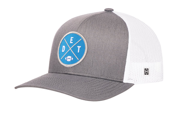 Gray and white trucker hat with blue DET X logo patch, curved brim, and mesh back.