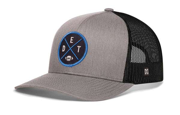 Gray-and-black trucker snapback cap with circular Detroit-style logo patch and mesh back