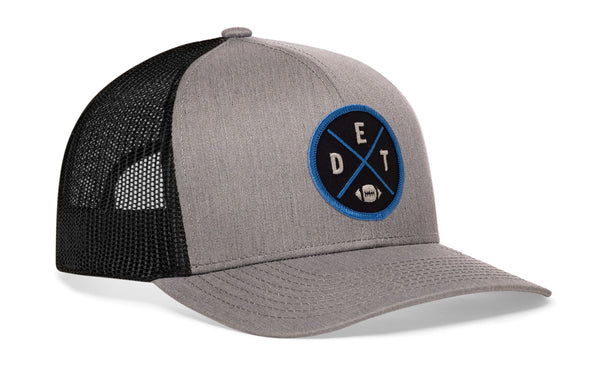 Gray-and-black trucker snapback cap with circular Detroit-style logo patch and side mesh panels