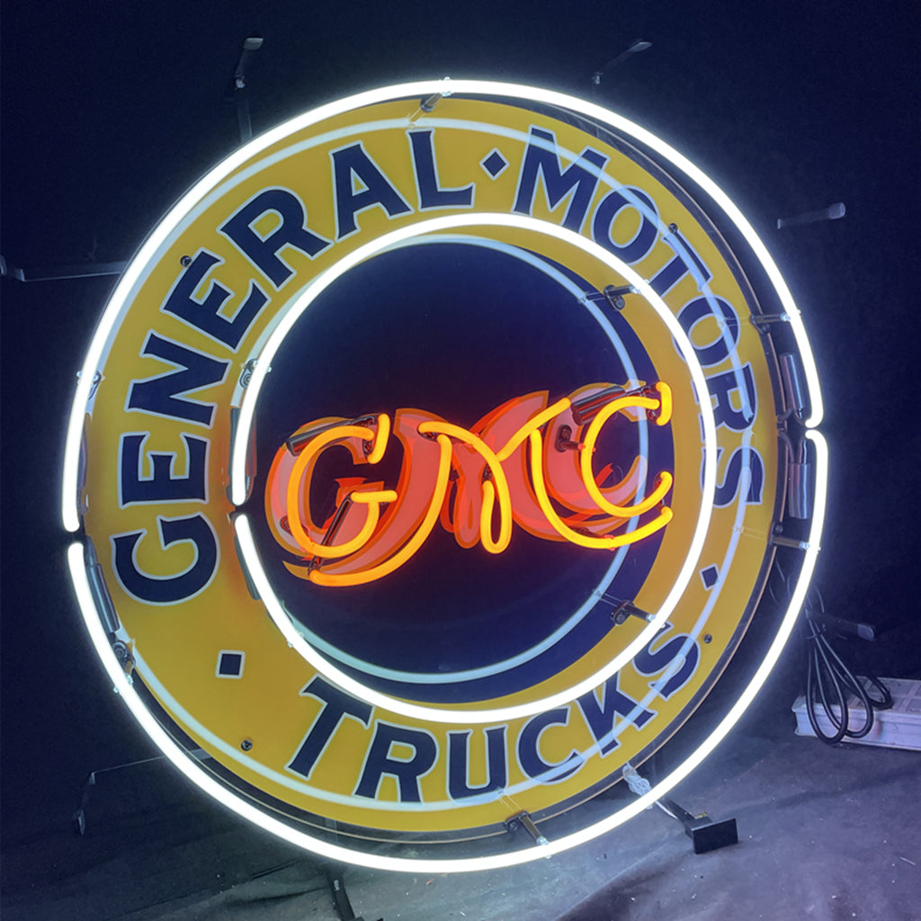 Neon circular sign with 'General Motors' ring text and 'Trucks' beneath GM CMC logo.