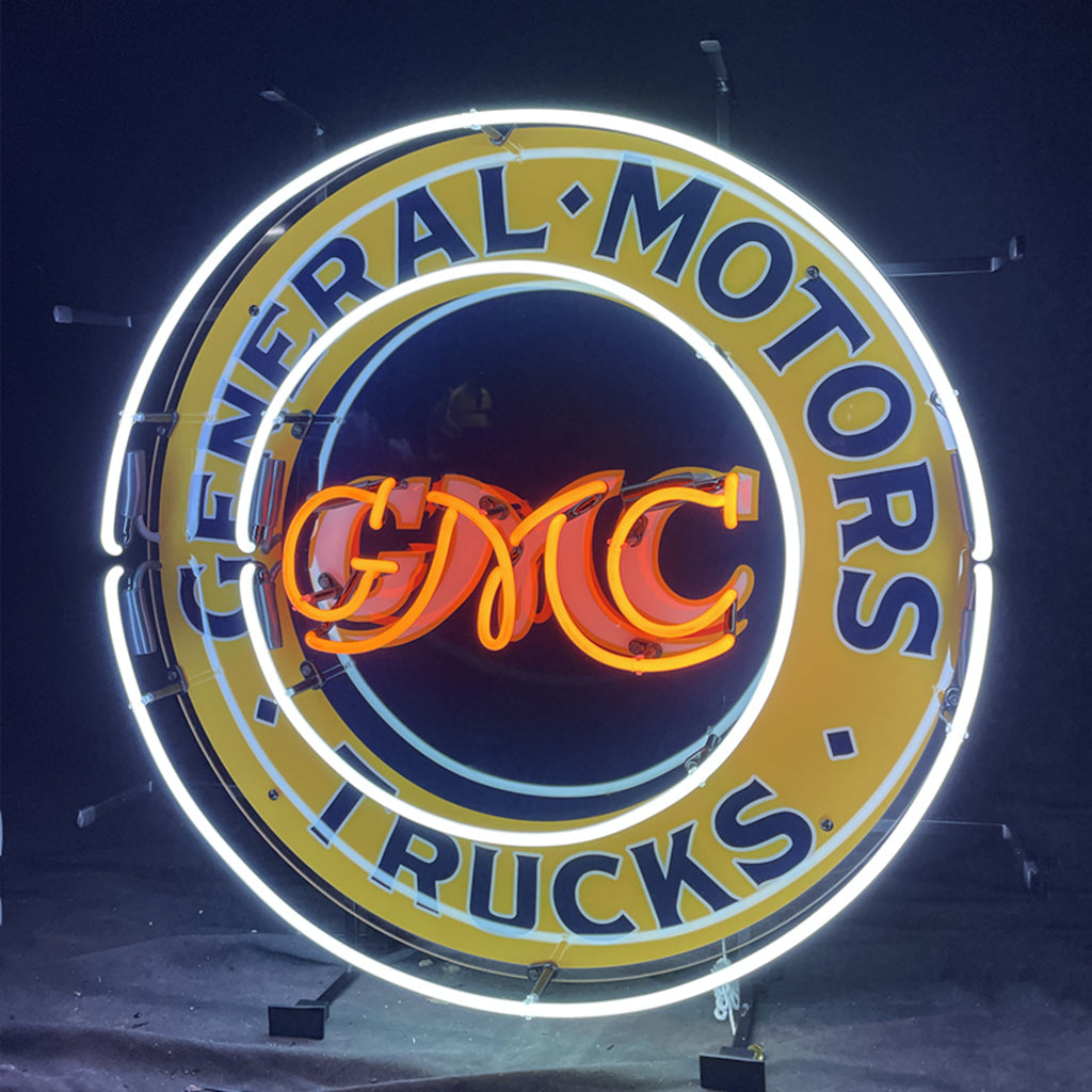 Neon circular sign with 'General Motors' and 'Trucks' text around GM CMC logo.