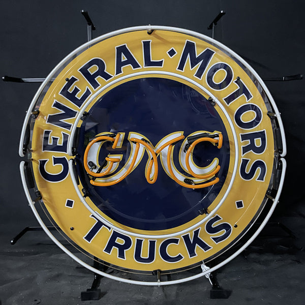 Front view neon circular sign with 'General Motors' and 'Trucks' ring text, GM CMC logo.