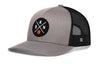 Gray trucker cap with front circular logo patch, black mesh side panels, curved brim