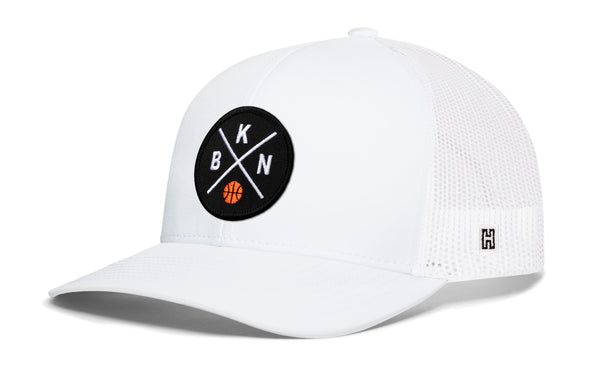 White trucker cap with circular front logo patch and white mesh side panels, curved brim
