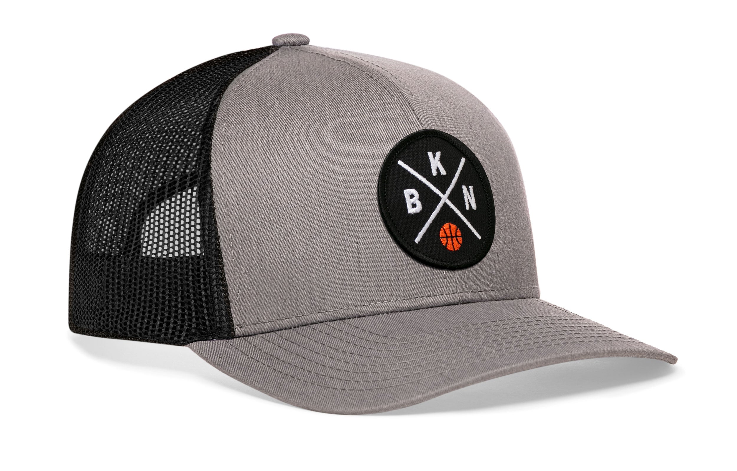 Gray front trucker cap with circular logo patch, black mesh side panels, curved brim