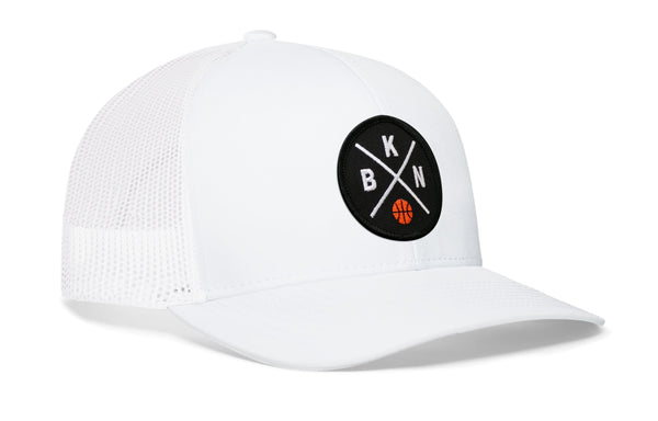 White trucker cap with circular front logo patch, white mesh side panels, curved brim