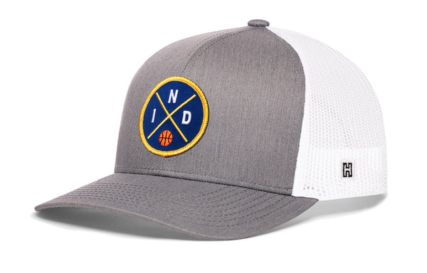 Gray-and-white trucker snapback hat with front circular logo patch and mesh back panel.
