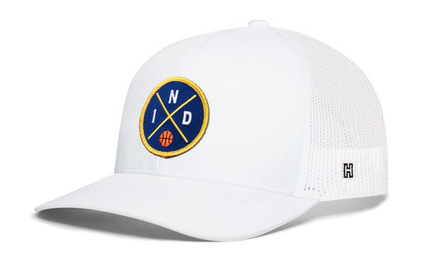 White trucker snapback hat with front circular logo patch and mesh back panel.