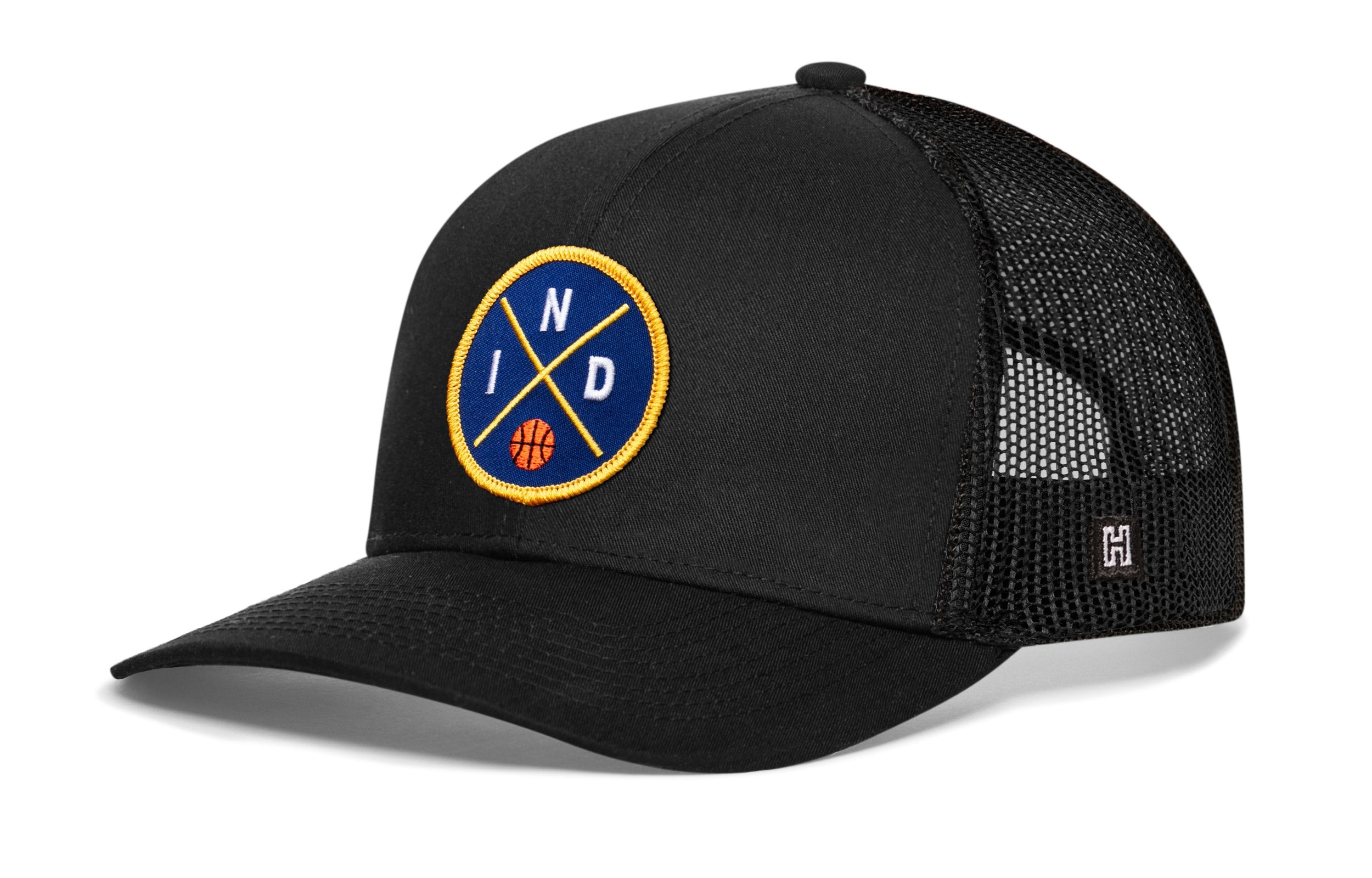 Black trucker snapback hat with front circular logo patch and mesh back panel.