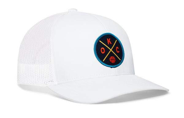 White trucker hat with mesh sides and circular team logo patch on the front panel.