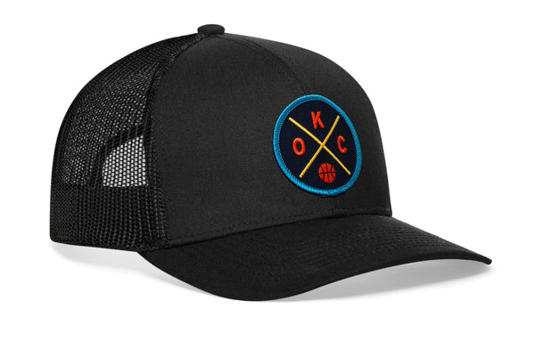 Black trucker hat with mesh sides and circular team logo patch on the front panel.