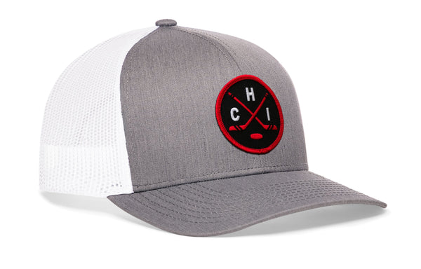 Gray trucker cap with white mesh back and red-and-black circular emblem patch on front.