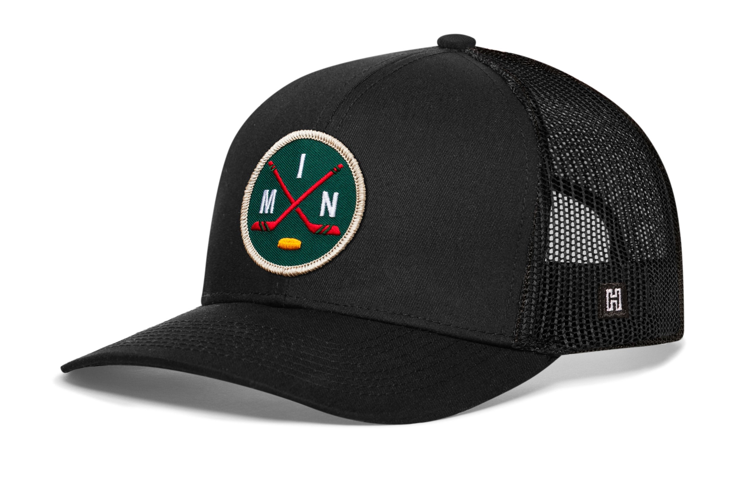 Black trucker hat with round hockey logo patch and mesh side panel, snapback closure.