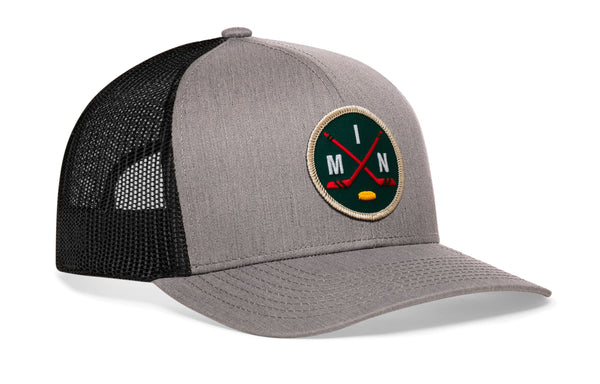 Gray trucker hat with black mesh back and round hockey logo patch on front, curved brim.