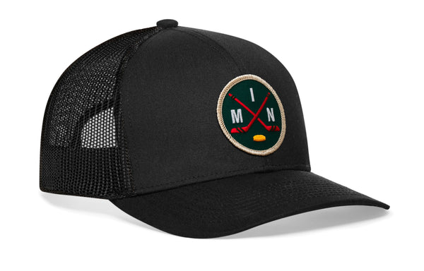 Black mesh trucker hat with round hockey logo patch on front panel and curved brim.