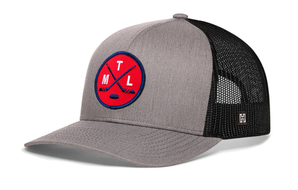 Gray trucker hat with black mesh sides, curved brim, and red circular crest patch on front