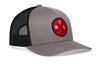 Gray trucker hat angled view with black mesh sides, curved brim, and red circular crest patch