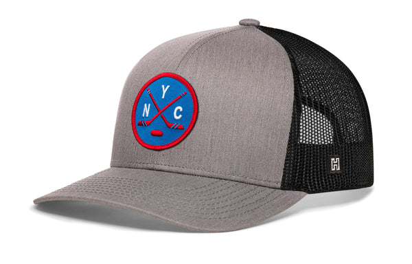 Gray hockey trucker hat with circular front patch, black mesh back, snapback closure.