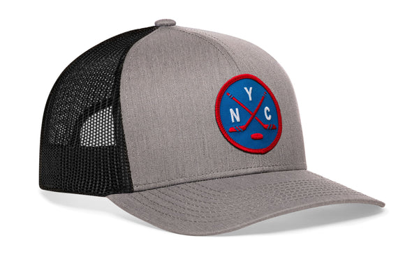 Gray hockey trucker hat with circular front patch, black mesh side panels, snapback.