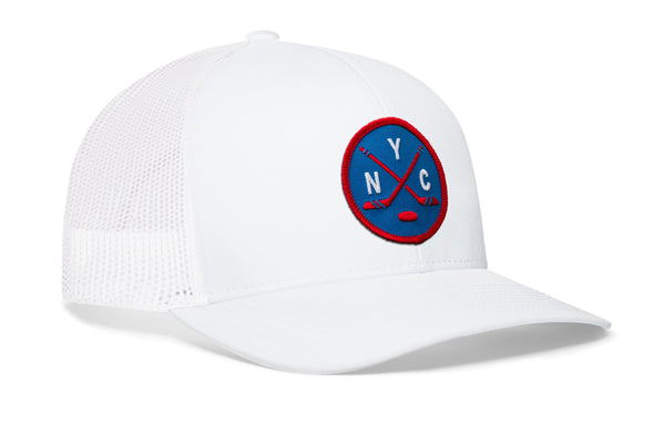 White hockey trucker hat with circular logo patch, mesh back, curved brim.