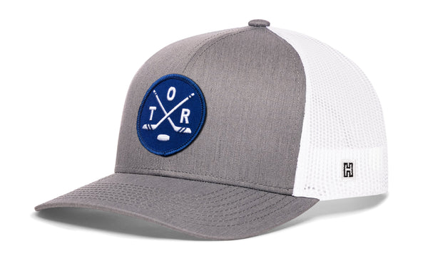 Gray-and-white trucker snapback hat with mesh sides, blue logo patch, and H emblem.