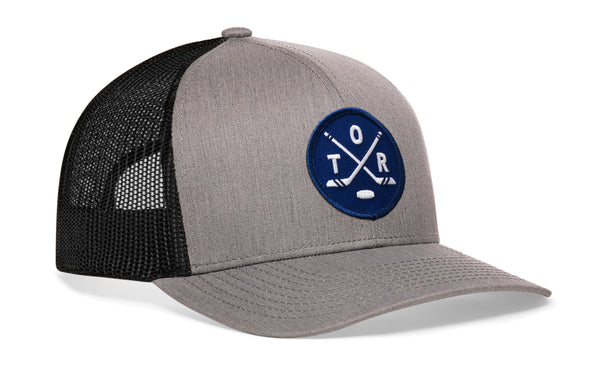 Gray trucker snapback hat with black mesh side, blue logo patch, and H emblem.