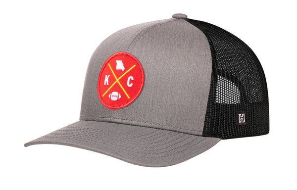 Gray trucker cap with red logo patch and black mesh side panels