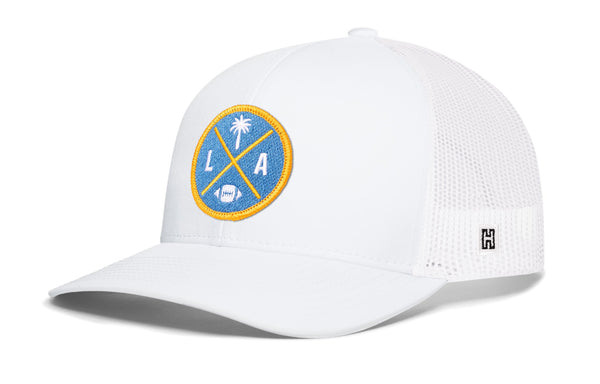White trucker cap with LA X logo patch, white mesh side panels, snapback closure