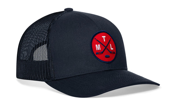 Navy trucker hat angled view with black mesh sides, curved brim, and red circular crest patch
