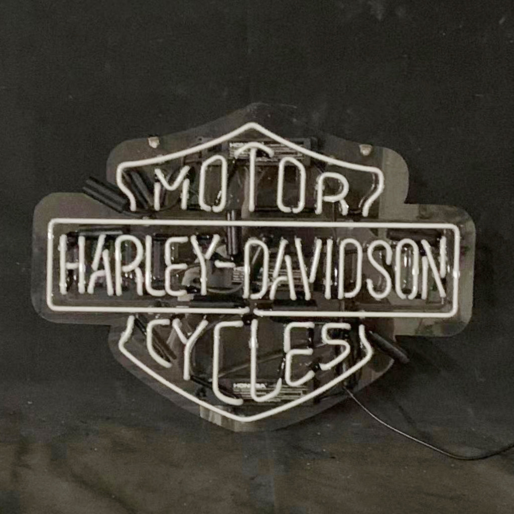 Harley-Davidson motorcycle neon sign with white-blue glow on dark backdrop and cable