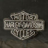 Harley-Davidson motorcycle neon sign with white-blue glow on dark backdrop and cable