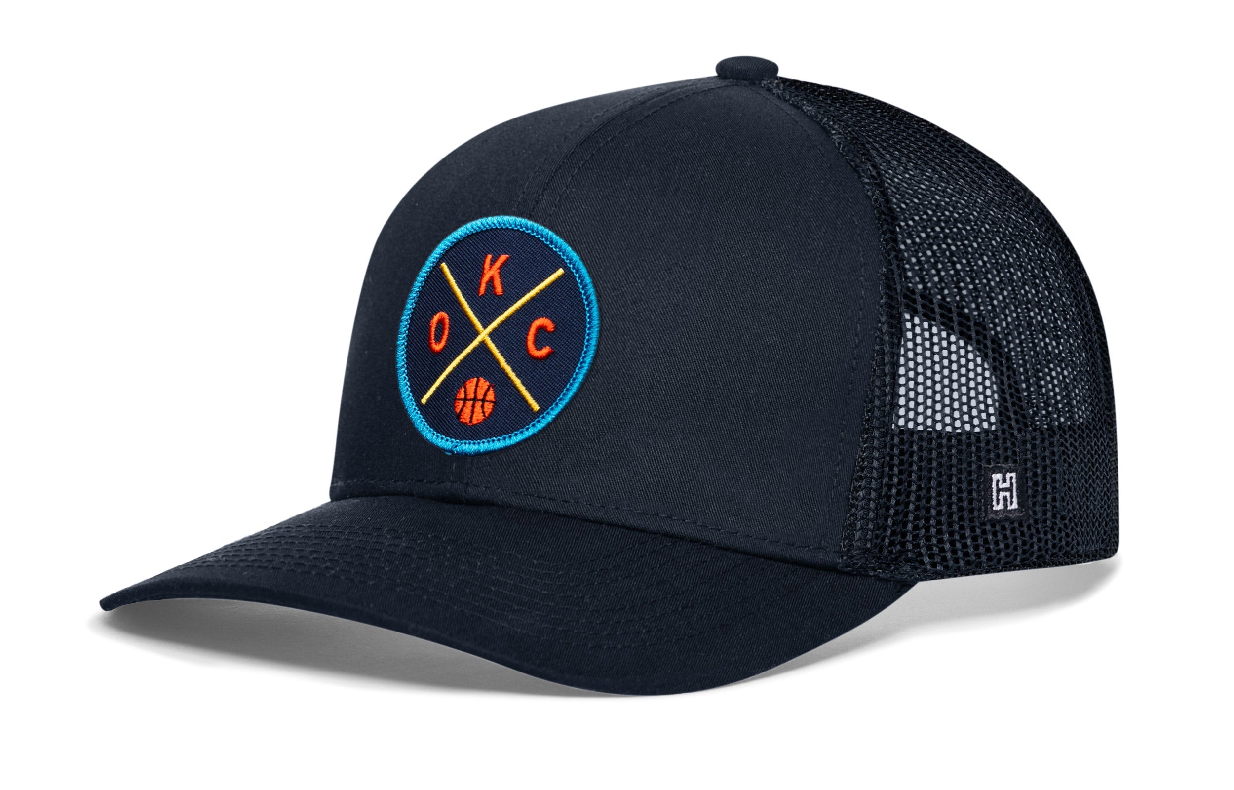 Black trucker hat with circular team logo patch, mesh sides, and curved brim.