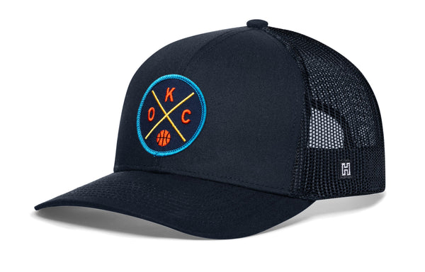 Black trucker hat with circular team logo patch, mesh sides, and curved brim.