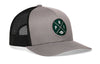 Gray front trucker hat with green round logo patch and black mesh back, snapback