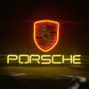 Porsche neon car sign featuring shield emblem above glowing PORSCHE lettering in yellow/red