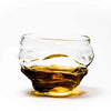 Crystal whisky glass with amber base liquid and clear wavy top rim.