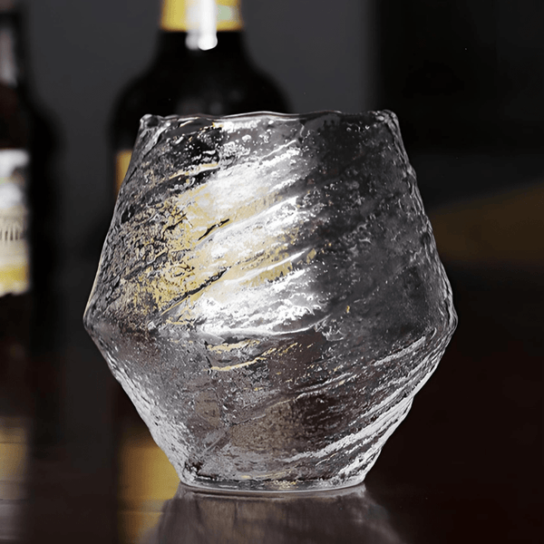 Faceted crystal whisky glass with amber liquid, clear smoky textured surface
