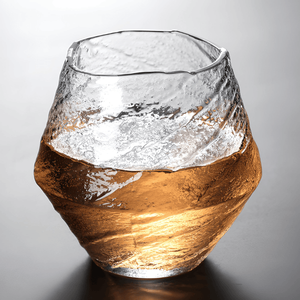 Faceted crystal whisky glass with amber liquid, textured clear glass walls