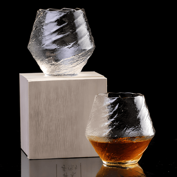 Faceted crystal whisky glass with amber liquid on a wood coaster